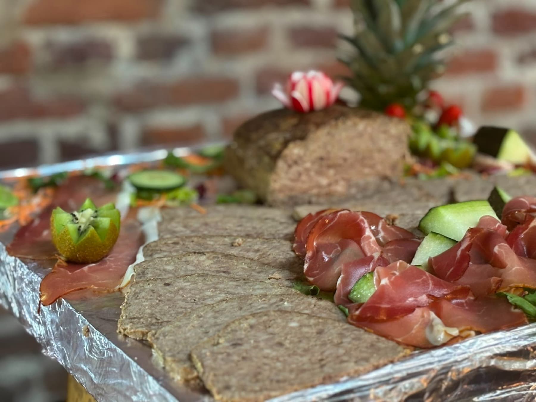 Planche de viandes froides et pâté maison sur fond de mur en briques