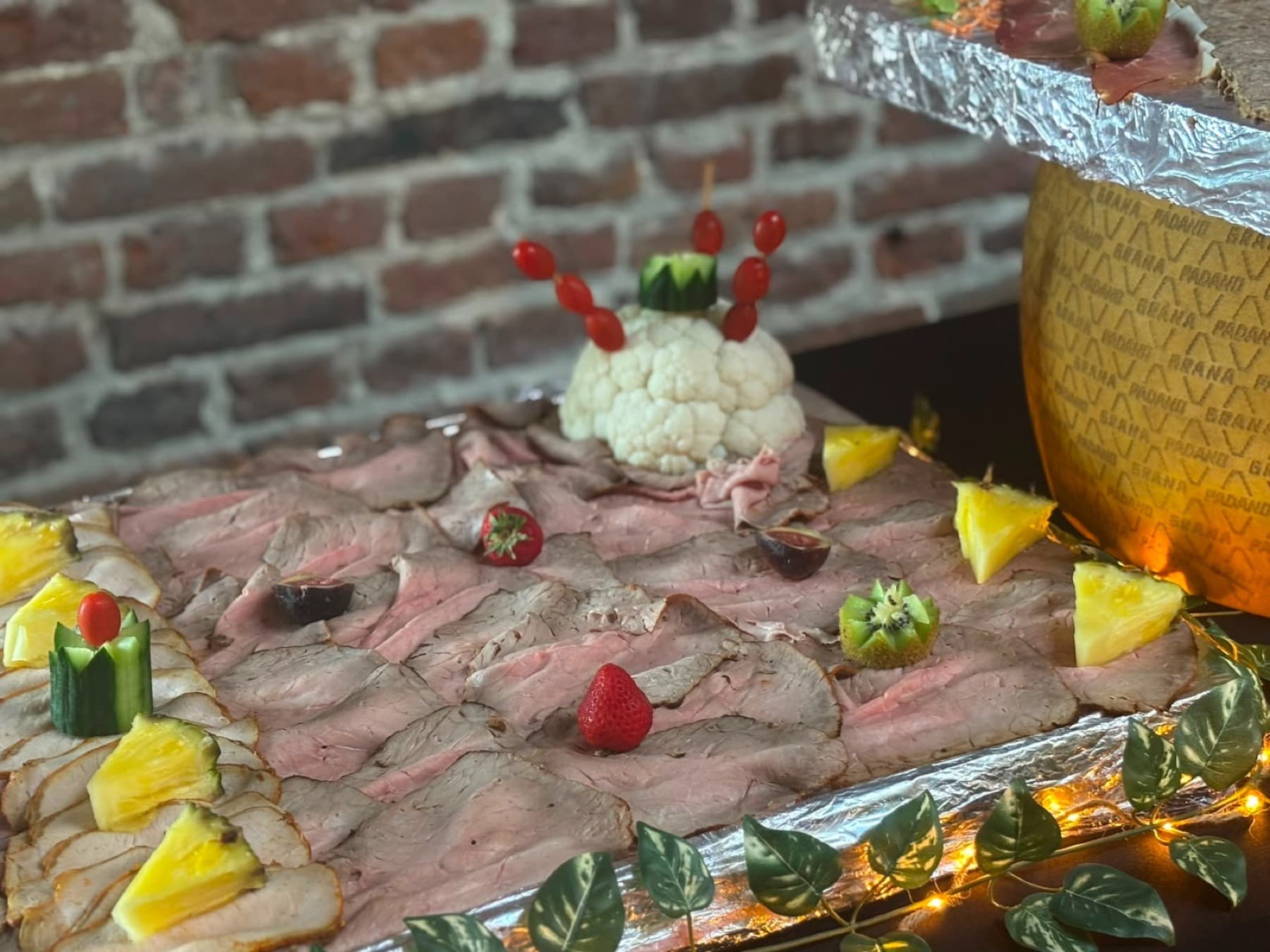 Buffet de rosbeef tranché décoré de fruits, meule de Grana Padano